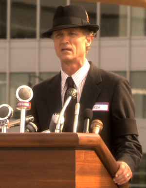 Caprica - Rebirth - Ken at Mic.png