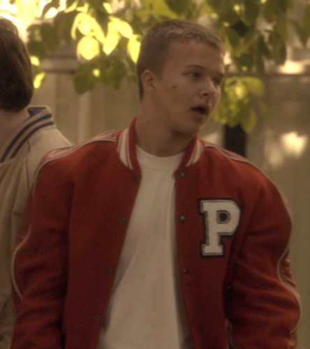 Fidgety student outside of Promethia High School in the school's varsity jacket, as seen by Joseph Adama from his vehicle (CAP: "Rebirth").