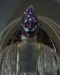 Lucifer sits on the throne in Baltar's absence.