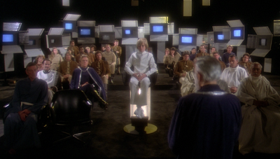Adama, Xaviar, and other VIPs in Zee's chamber aboard Galactica watch repurposed footage from Earthquake, modified to show a hypothetical Cylon attack on Earth (1980: "Galactica Discovers Earth, Part I").